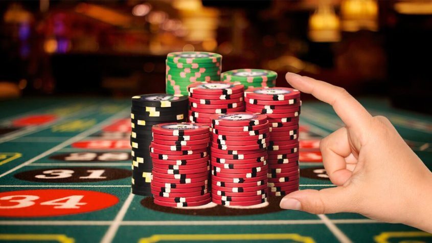 A Hand Placing a Stack of Casino Chips on a Roulette Table