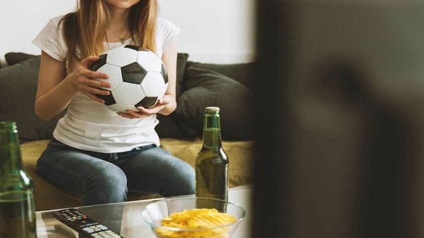 Person on Couch Holding Soccer Ball Watching Tv